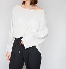 Wall Mural - Young woman wearing stylish outfit with a white oversized shirt and black high-waisted trousers isolated on light grey background. Copy space