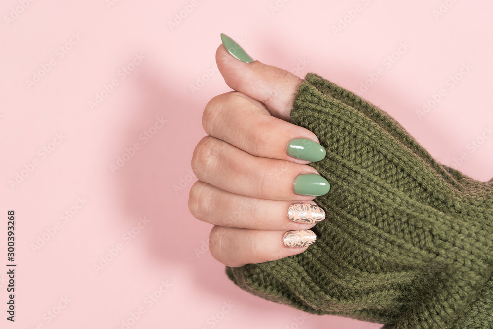 Closeup top view of beautiful two faded colors trendy manicure of green,  pink nails with glossy silver stamping design isolated on pastel pink  background. Winter, autumn style of nail design concept. Stock-foto |