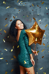 Beautiful young african woman having fun and holding golden balloon