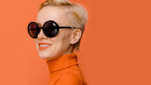 Beauty Portrait Of Female Model Wearing Trendy Sunglasses Over Orange Background