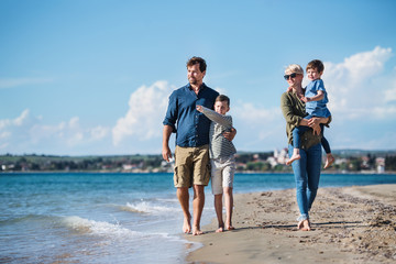 Wall Mural - Young family with two small children walking outdoors on beach.