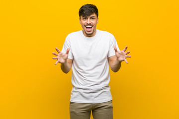 Young hispanic casual man celebrating a victory or success, he is surprised and shocked.