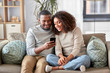 © Syda Productions - technology, internet and people concept - happy african american couple with smartphone at home