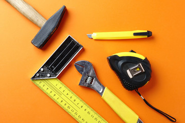 Hammer, carpenter?s corner, tape measure on an orange background