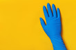 © Olga - Hand in a protective blue glove on a yellow colored background