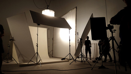 Wall Mural - Silhoutte images of video production and lighting set for filming which movie crew team working and silhouette shadow of camera and professional equipment in big studio for commercial advertising.
