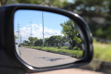 Pathway Electric Poles Trees And Clear Clouds In Sky Seen Through Back View Mirror Of Car