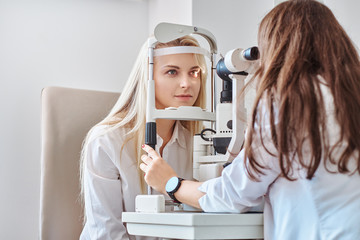 attractive woman is doing eye test in optical clinic with experienced oculist.