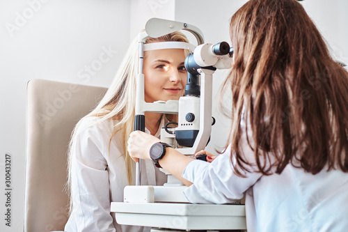 Fotografía Attractive woman is doing eye test in optical clinic with experienced oculist