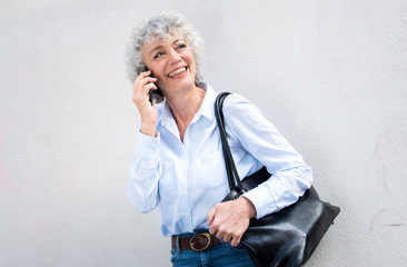 Wall Mural - happy middle aged woman talking with cellphone by white wall