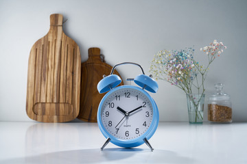 Natural wooden kitchen spoons for bread stand on a gray background, in the foreground stands blue alarm clocks