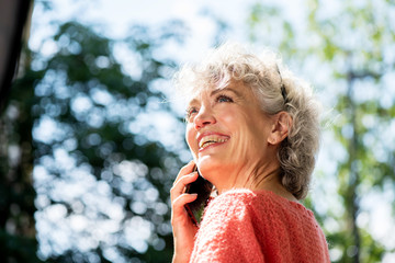 Wall Mural - happy attractive middle aged woman talking with cellphone outdoors