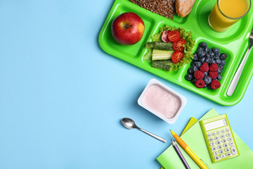 serving tray of healthy food and stationery on light blue table, flat lay with space for text. schoo