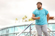© New Africa - Young overweight man in sportswear outdoors. Fitness lifestyle