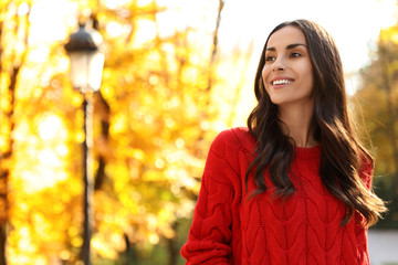 Wall Mural - Beautiful woman wearing red sweater in sunny park. Autumn walk