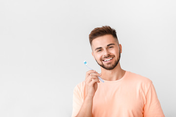 Portrait of man brushing teeth on light background