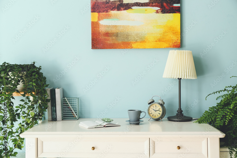 Modern stylish workplace with green plants near color wall