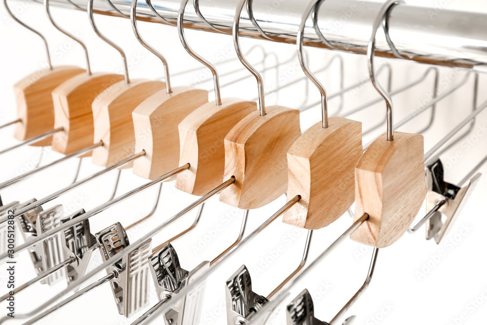 Rack with clothes hangers on white background, closeup