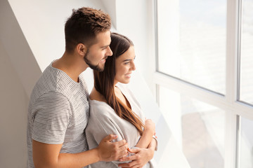 Portrait of beautiful young couple near window at home