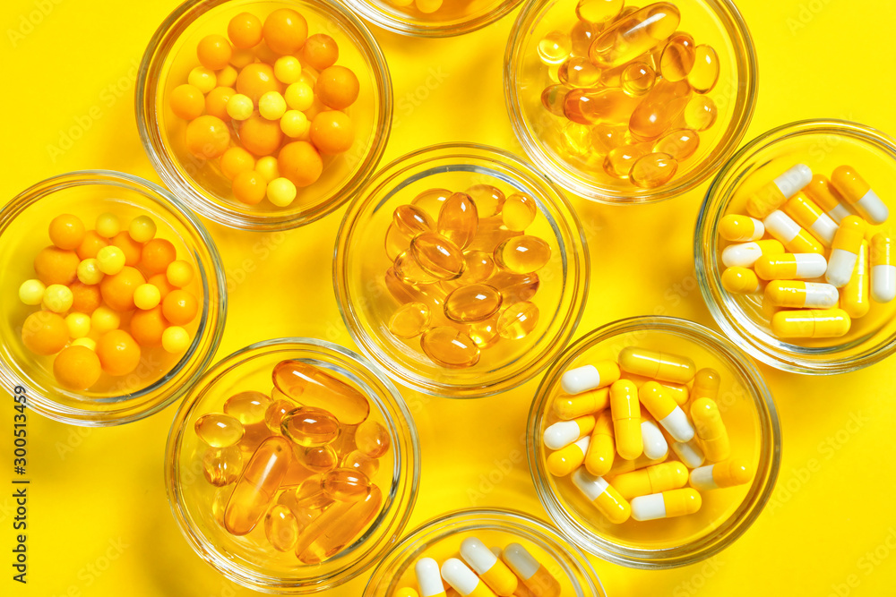 Bowls with different pills on color background