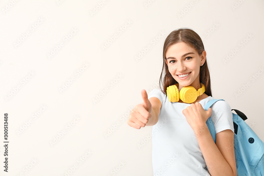 Beautiful female student showing thumb-up on white background