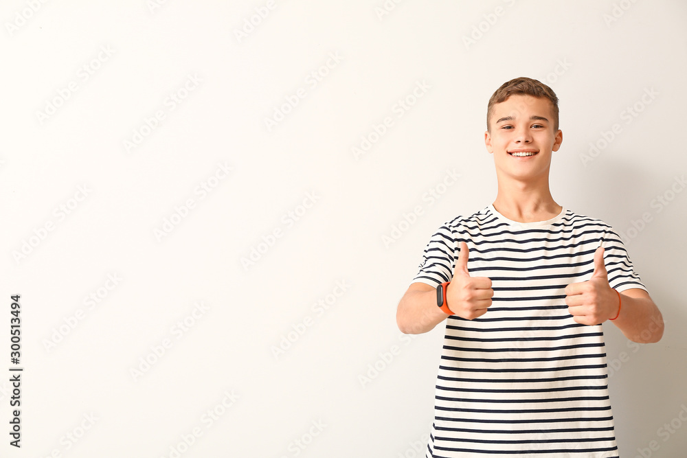 Cool teenage boy showing thumb-up on white background