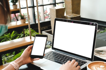 mockup image computer,cell phone blank screen for hand typing text,using laptop contact business searching information in workplace on desk at office.design creative work space on wooden desk