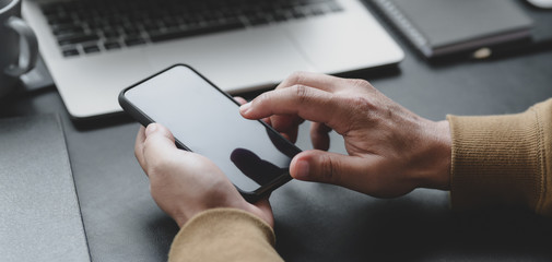 Canvas Print - cropped shot of professional businessman touching smartphone in his dark luxury workspace
