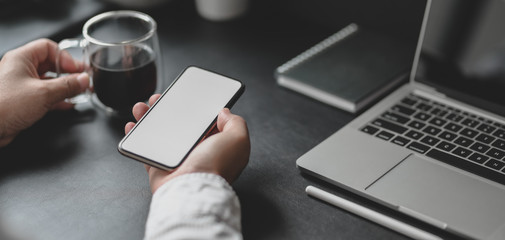 Canvas Print - close-up view of professional businessman holding smartphone while drinking a cup of coffee