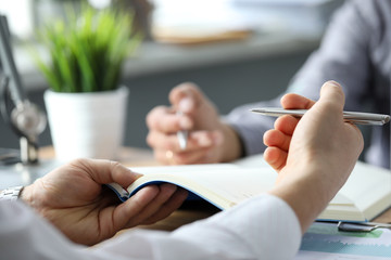 two clerks discussing business using notebooks and pens