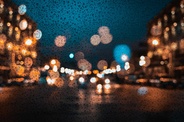 Wall Mural - raindrops on window of car with the rainy season in blur night city background.