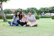 © xreflex - Group Cheerful young Asian woman in casual clothes three people sit in the park Look at the camera. Happy vacations