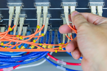 Technician connect fiber cable network to switch port in server room , Concept internet network management