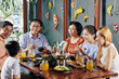 © DragonImages - Happy big Asian family talking, laughing and eating good food at dinner