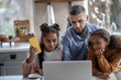 © zinkevych - Lovely daughters standing near daddy working on laptop