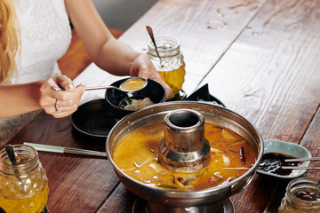 Poster - Cropped image of yuong woman eating delicious squid soup with noodles for dinner