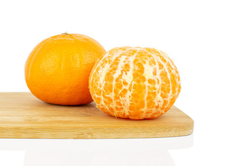 Group of two whole fresh orange mandarine on bamboo cutting board isolated on white background