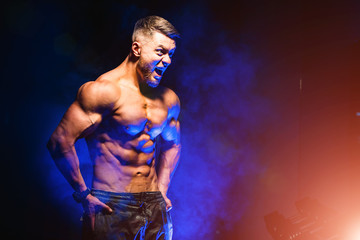 Brutal strong athletic men pumping up muscles. Workout and bodybuilding concept. Blue light filter. Handsome man with naked torso. Fitness model is posing.