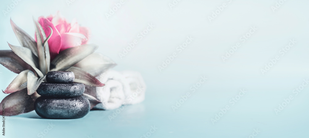 Spa and wellness concept with stack of zen stones, flowers and towels at light blue background with copy space. Relax and calm  treatment. Still life. Banner - obrazy, fototapety, plakaty 