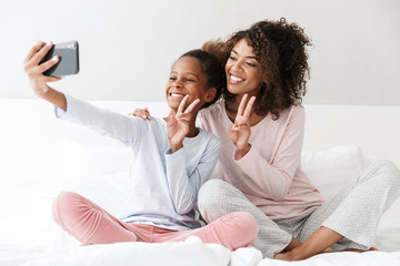 Canvas Print - Image of american woman and little daughter taking selfie at home