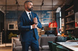 © opolja - Stylish bearded man in a suit standing in modern office