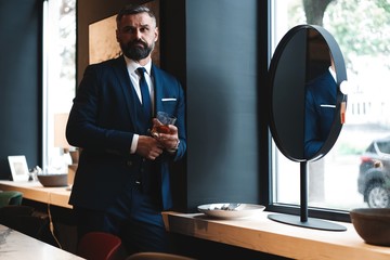 Wall Mural - Stylish bearded man in a suit standing in modern office