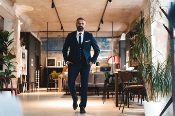 Wall Mural - Stylish bearded man in a suit standing in modern office