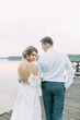 © pavelvozmischev - Stylish European wedding at sunset. Happy couple on the pier on the lake.
