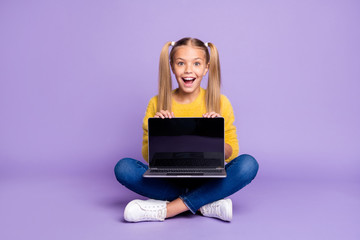 Full size photo of amazed excited child show laptop show touch screen scream wow omg sit crossed folded legs wear casual style outfit isolated over violet color background