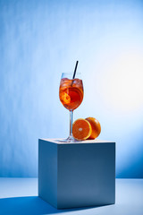 Wall Mural - cocktail Aperol Spritz with straw in glass and oranges on blue background