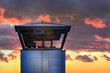 An air traffic control tower with the silhouette of an unidentifiable male traffic controller standing, cloudy weather, Iceland.