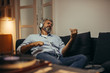 © cherryandbees - mid aged man relaxing in his home listening to a music