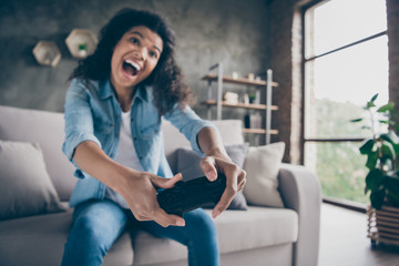 Poster - Blurry focus photo of funny pretty dark skin wavy lady hold gamepad console joystick addicted gamer excited sitting cozy couch casual denim outfit living room indoors