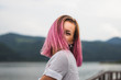 Woman with pink hair standing on the mountain top over blue sea view, photo toned